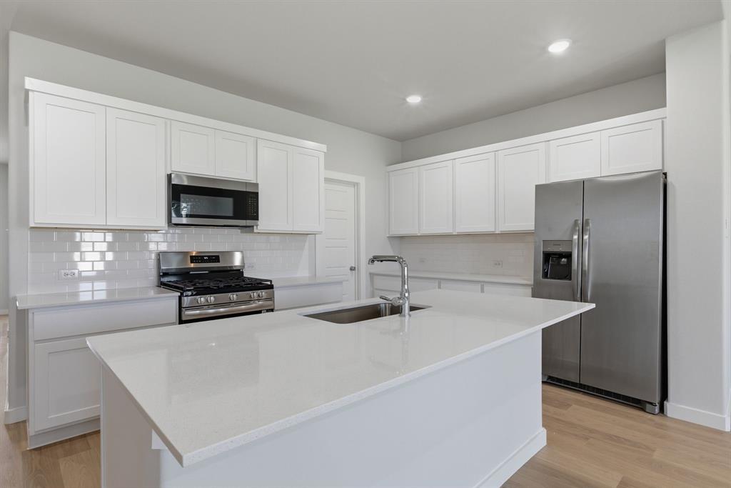 637 Sierra Ridge Lavon, TX 75166 - Photo 7 of 26 a kitchen with stainless steel appliances a stove a sink a microwave and a refrigerator