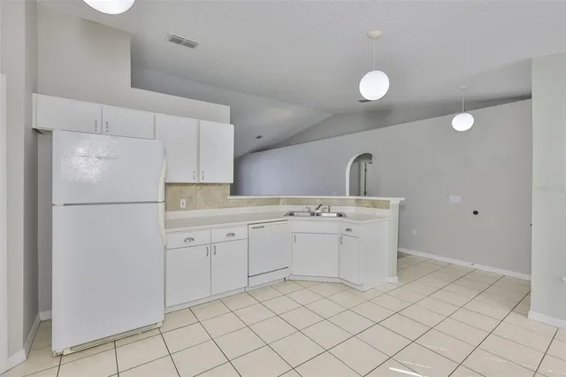 a kitchen with white cabinets and refrigerator