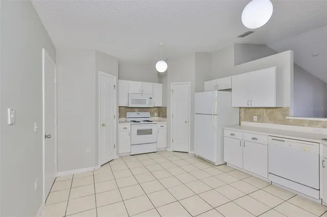 a kitchen with white cabinets and appliances