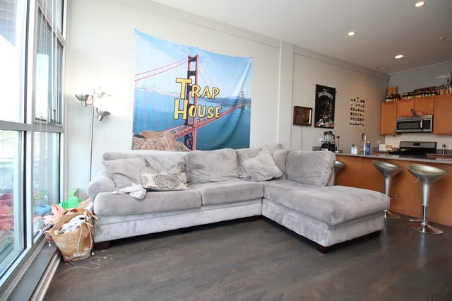 a living room with stainless steel appliances kitchen island granite countertop furniture and a wooden floor