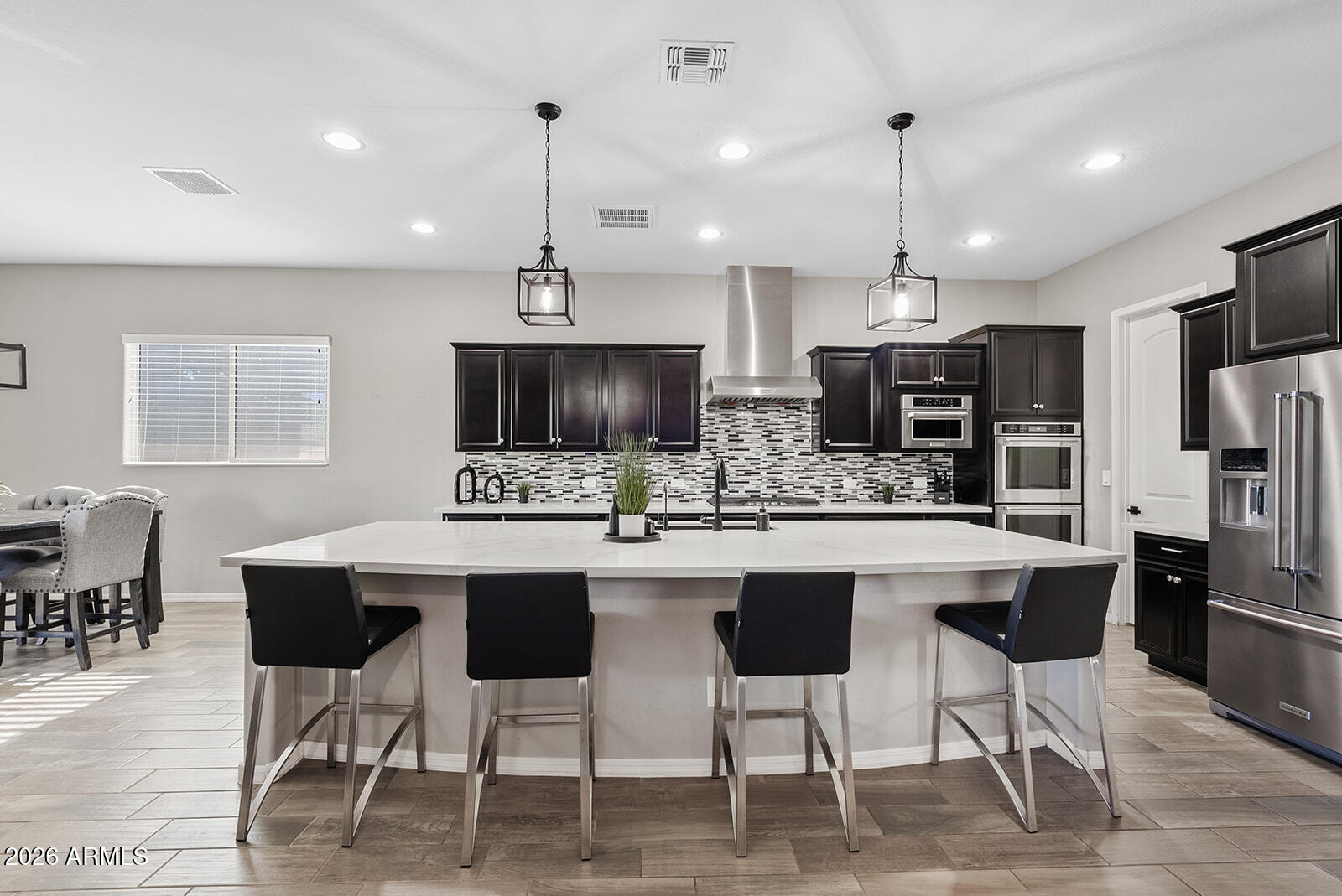 19411 East Timberline Road Queen Creek, AZ 85142 - Photo 16 of 44 a kitchen with stainless steel appliances kitchen island granite countertop a dining table chairs refrigerator and sink