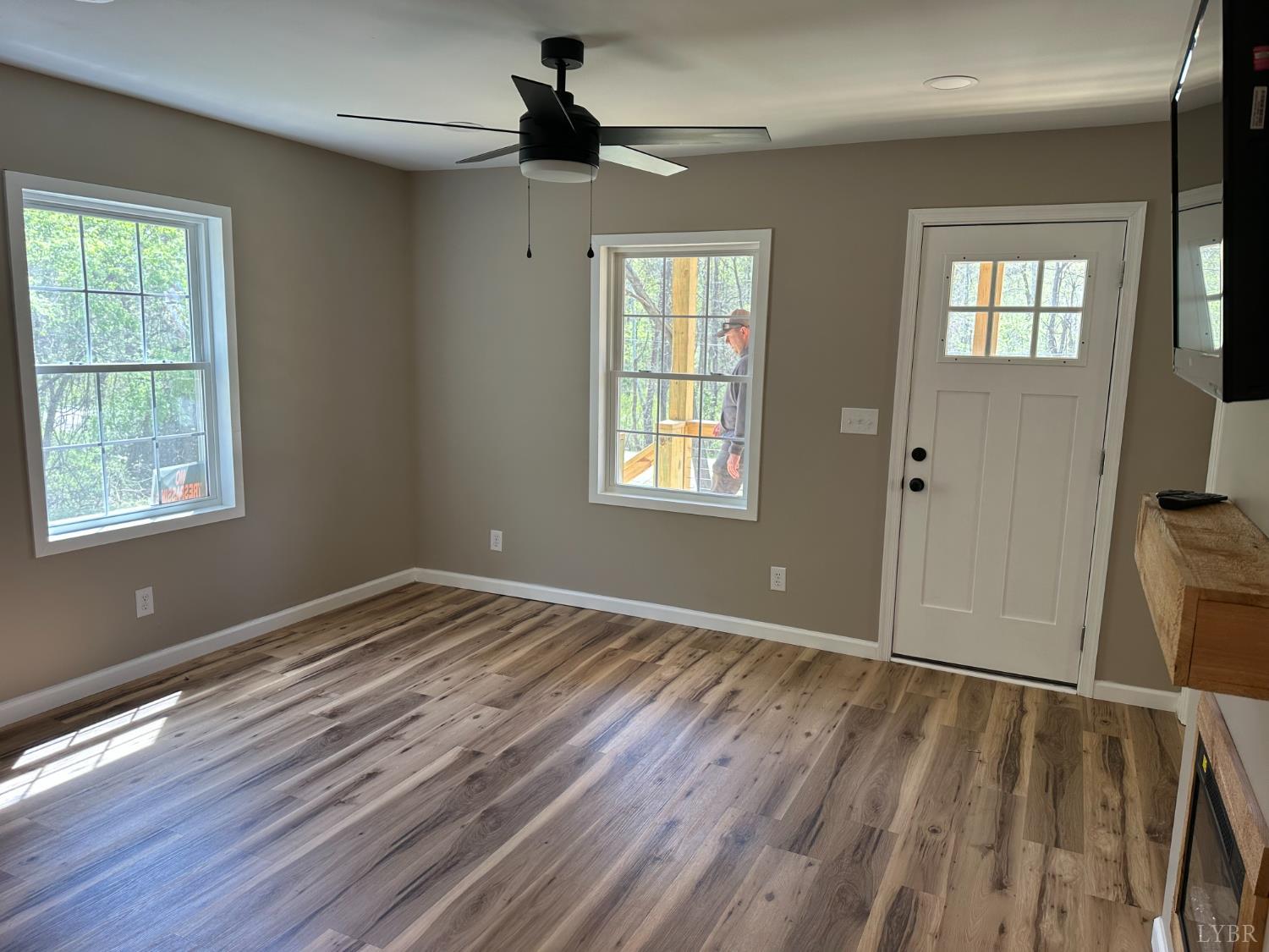 a view of an empty room with wooden floor and a window