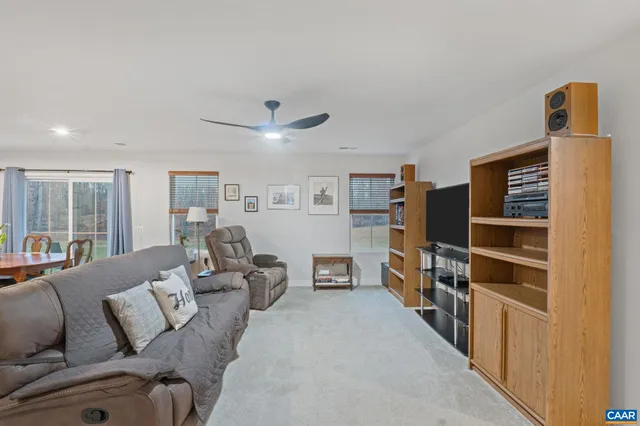 a living room with furniture a flat screen tv and a refrigerator