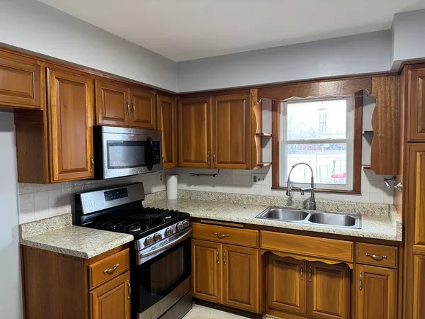 a kitchen with granite countertop a stove a sink and a microwave
