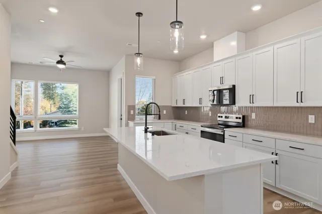 a large white kitchen with lots of counter space wooden floor and appliances