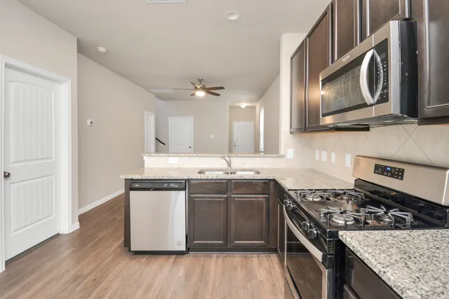 a kitchen with stainless steel appliances granite countertop a stove a sink and a microwave