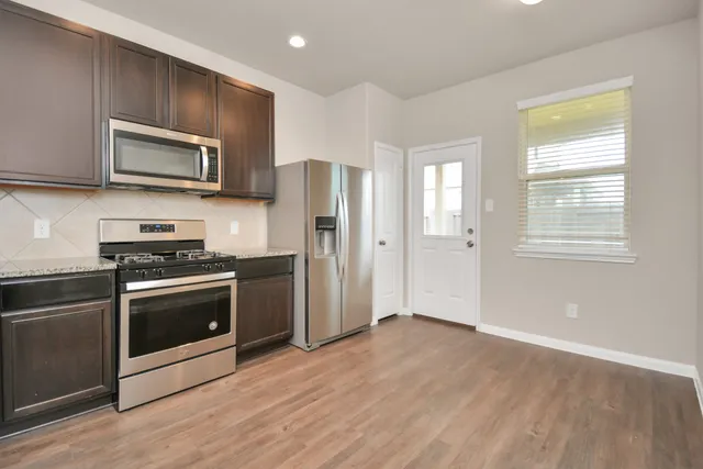 a kitchen with stainless steel appliances granite countertop a stove a refrigerator and a microwave