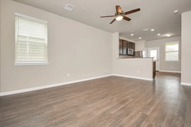 a view of empty room with wooden floor and fan