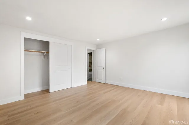 a view of an empty room with wooden floor & closet