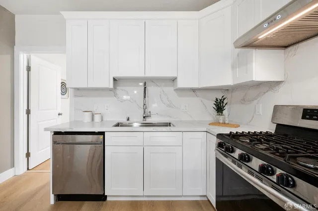a kitchen with granite countertop white cabinets and stainless steel appliances