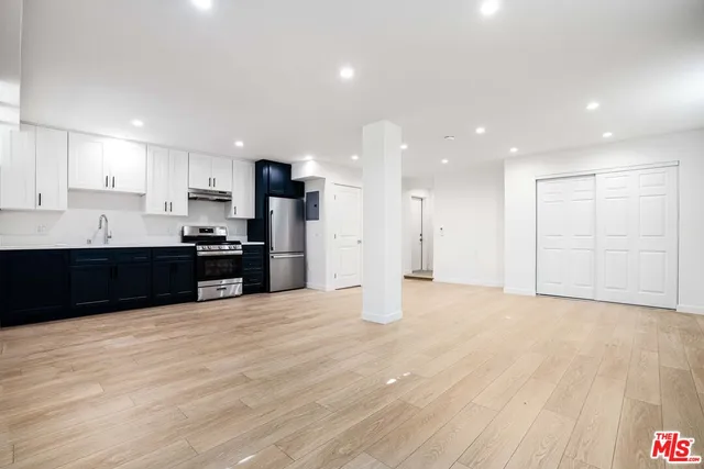 a view of kitchen with kitchen island granite countertop wooden cabinets and a sink