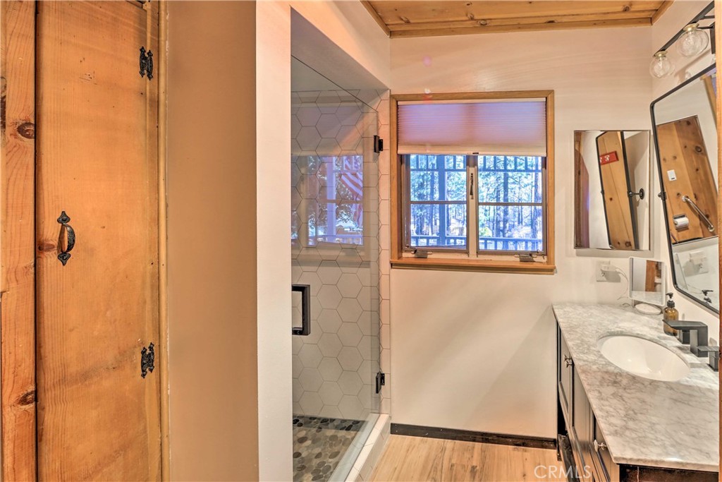 1069 Eagle Road Wrightwood, CA 92397 - Photo 12 of 24 a bathroom with a granite countertop sink a mirror and a shower