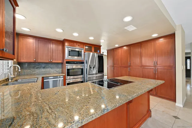 a kitchen with stainless steel appliances granite countertop sink stove refrigerator and cabinets