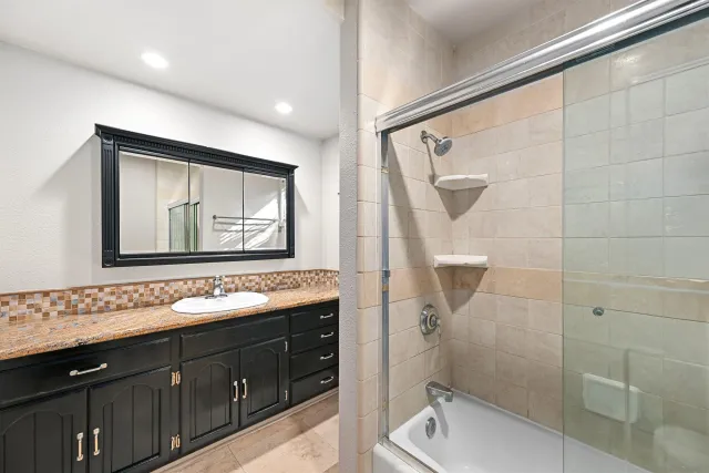 a bathroom with a sink vanity granite toilet and a mirror
