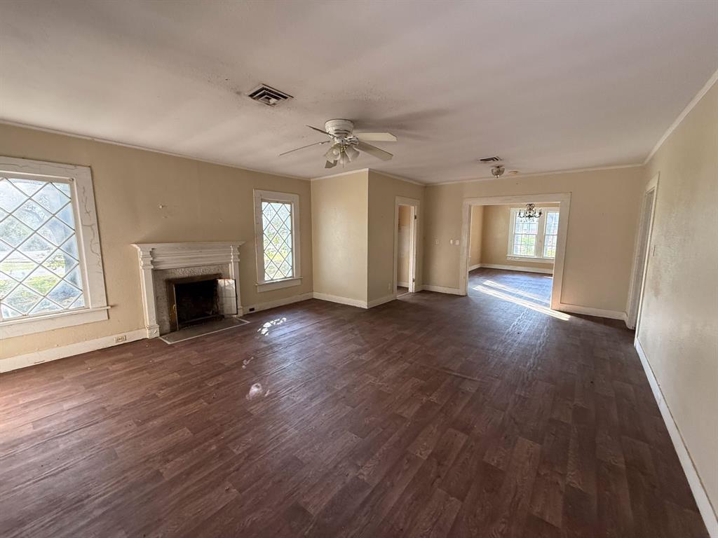 100 Smith Street Naples, TX 75568 - Photo 3 of 30 an empty room with wooden floor fireplace and windows