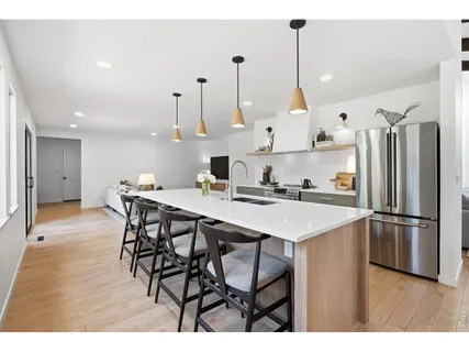 a kitchen with stainless steel appliances granite countertop a sink a stove a refrigerator and island with wooden floor