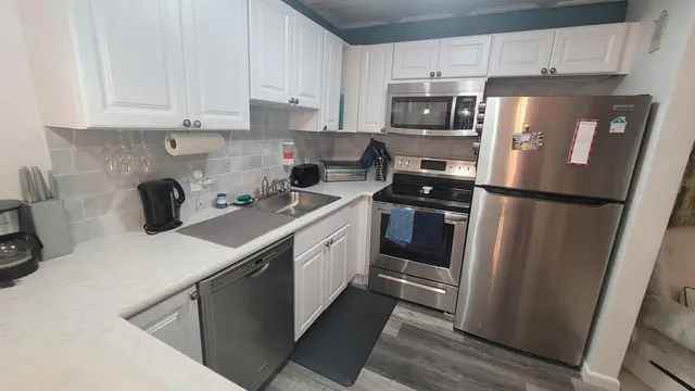 a kitchen with stainless steel appliances a refrigerator a sink a stove a microwave and cabinets