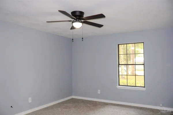 an empty room with a window and a fan