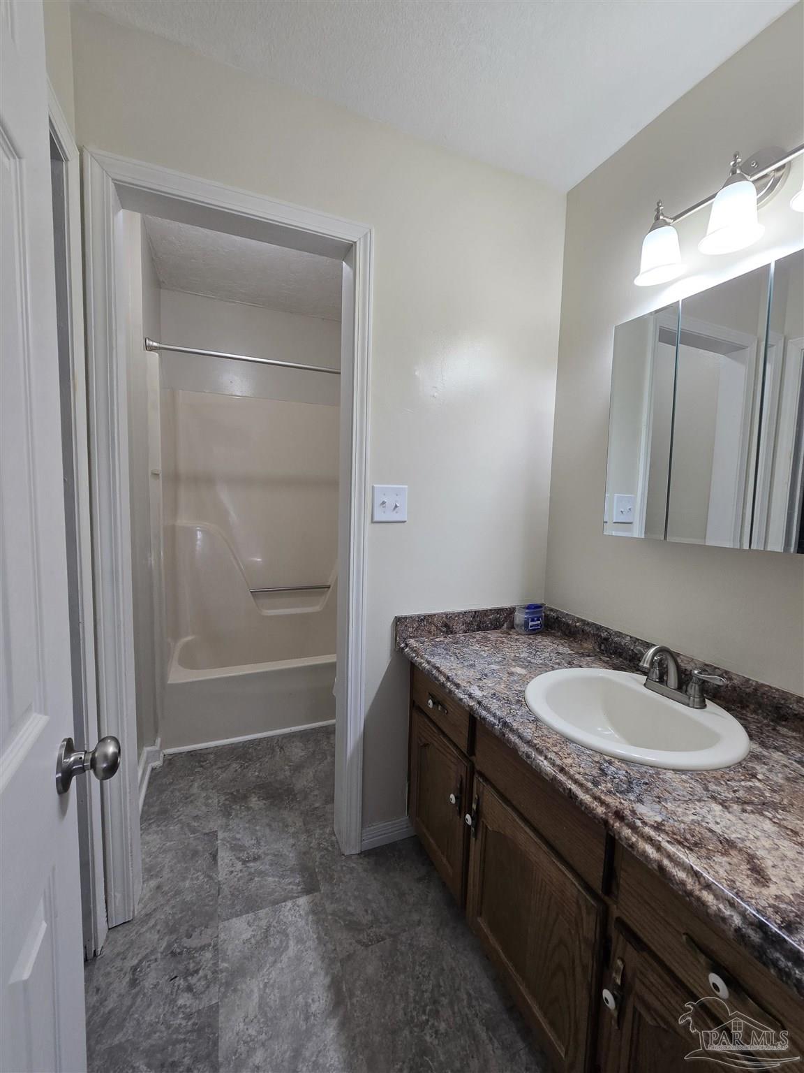 111 Cotton Creek Road McDavid, FL 32568 - Photo 16 of 30 a bathroom with a granite countertop sink a mirror and a shower