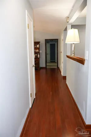 a view of a hallway with wooden floor and a refrigerator