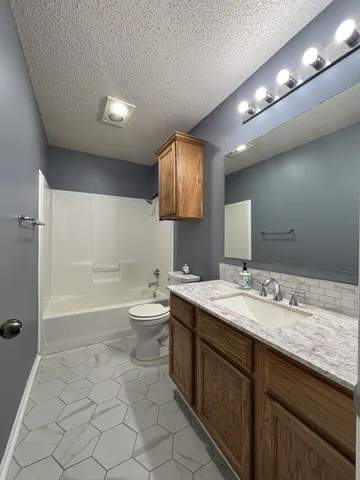 an empty room with chandelier fan and windows