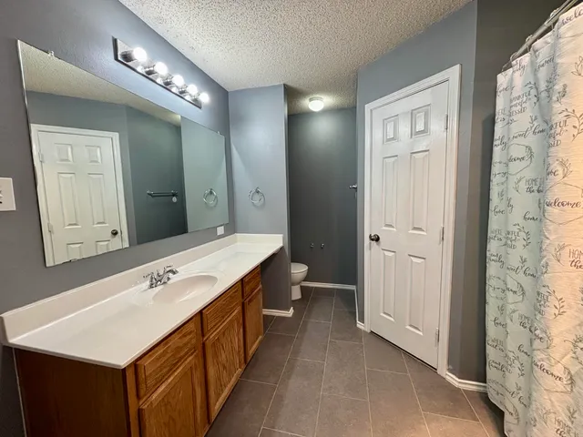 an empty room with chandelier fan and fire place
