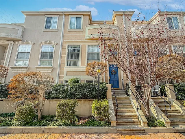 a front view of a multi story residential apartment building with yard and parking spaces