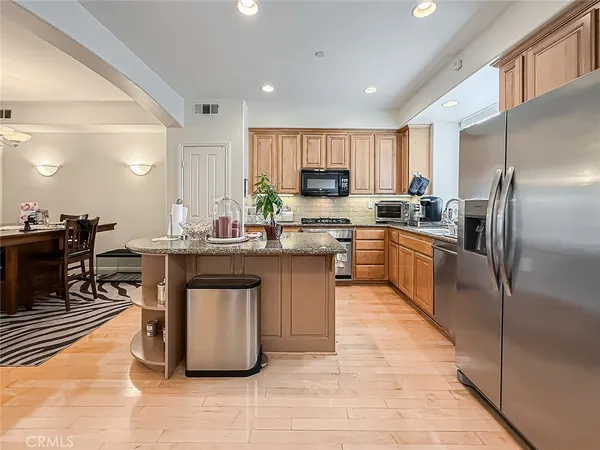 a kitchen with stainless steel appliances granite countertop a refrigerator a sink a stove and a refrigerator with wooden floor