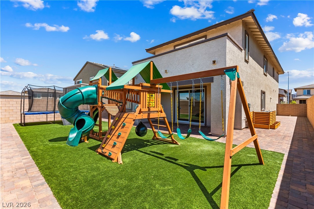 320 Isla Enclave Way Henderson, NV 89011 - Photo 36 of 49 This outdoor space offers a fun-filled environment with a playground and trampoline set on green artificial turf.