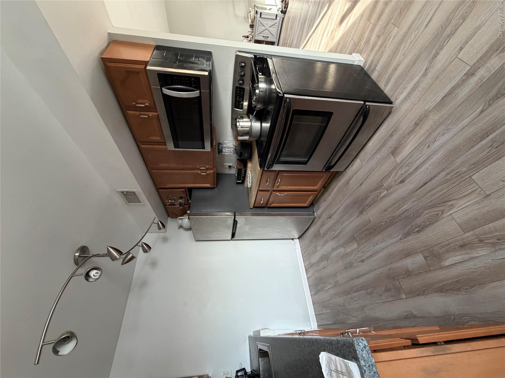 26 Cooper Road, Unit 312 Poughkeepsie, NY 12603 - Photo 11 of 13 a kitchen with stainless steel appliances a stove a microwave and wooden floors
