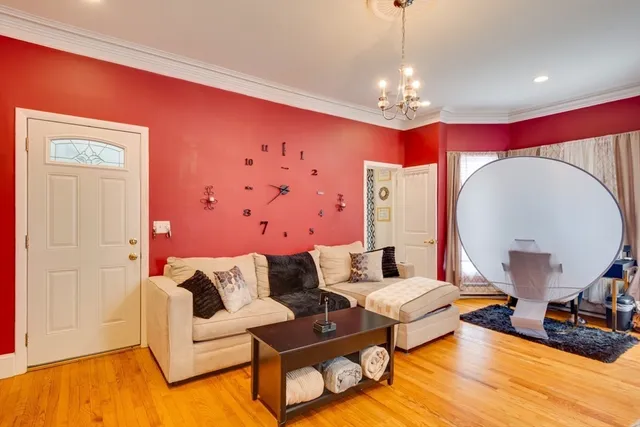 a living room with furniture a chandelier and a wooden floor