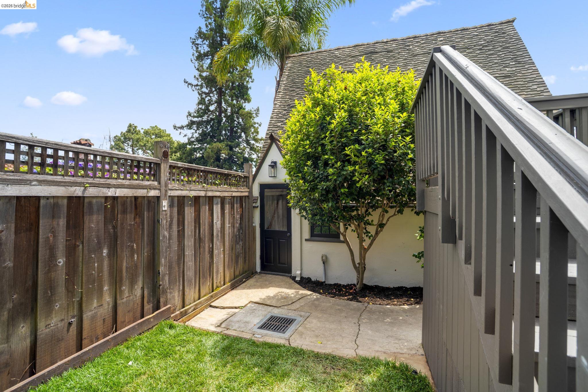 1087 Hubert Road Oakland, CA 94610 - Photo 38 of 67 Enclosed outdoor area featuring a wood fence with lattice accents, a patch of green lawn, and concrete paving leading to a dwelling