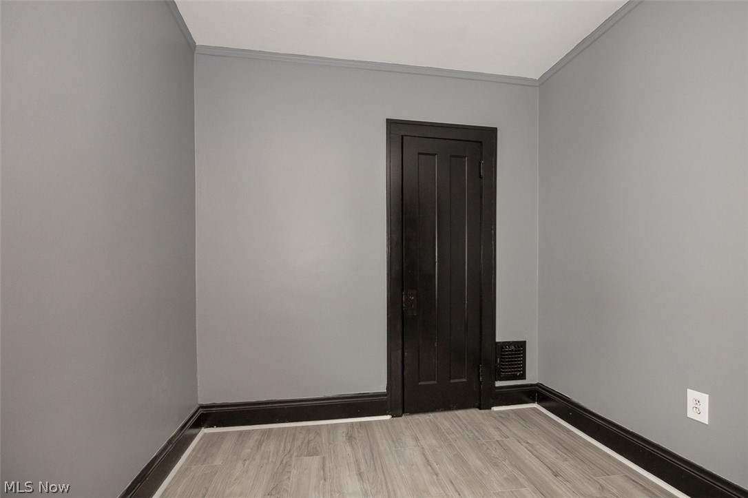 1868-1870 Lampson Road Cleveland, OH 44112 - Photo 16 of 36 Interior space featuring a dark paneled door, light gray walls, dark baseboards, and wood-finish flooring