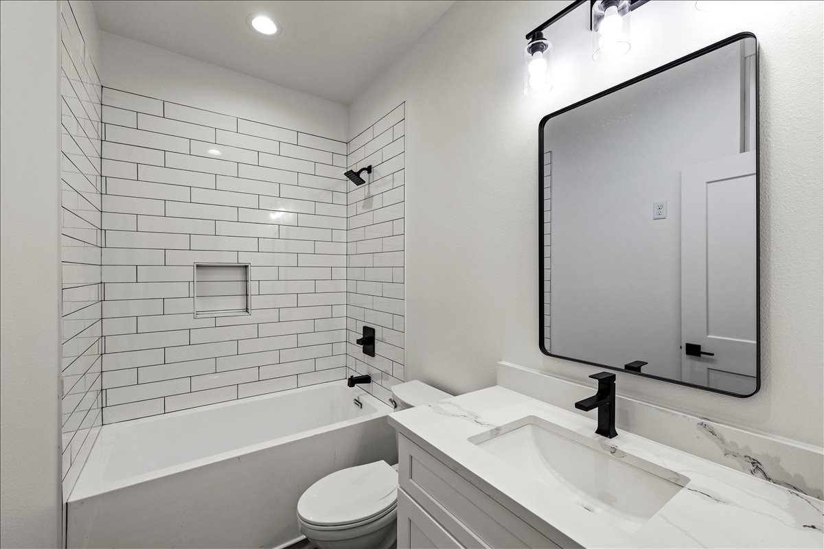 14103 3rd Street Santa Fe, TX 77517 - Photo 29 of 46 a bathroom with a sink a toilet a mirror and bathtub