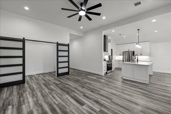 a view of a kitchen with stainless steel appliances granite countertop a refrigerator a sink dishwasher and a fireplace with wooden floor