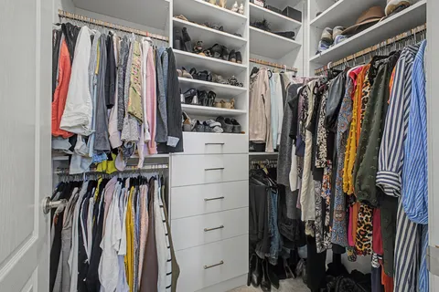 a view of walk in closet with clothes and shoes