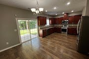4557 Ivy Patch Drive Fortson, GA 31808 - Photo 5 of 27 a large kitchen with kitchen island granite countertop a refrigerator a stove a sink a dining table and chairs with wooden floor