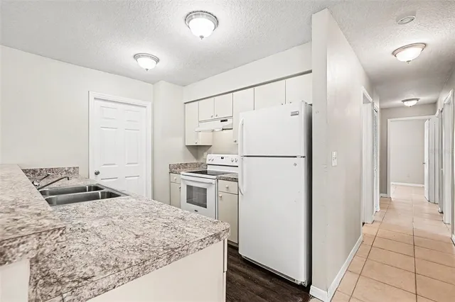 a kitchen with stainless steel appliances granite countertop a refrigerator a stove and a sink