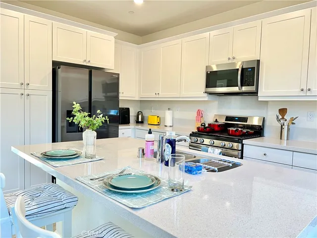 a kitchen with stainless steel appliances granite countertop a stove a refrigerator and a white cabinets
