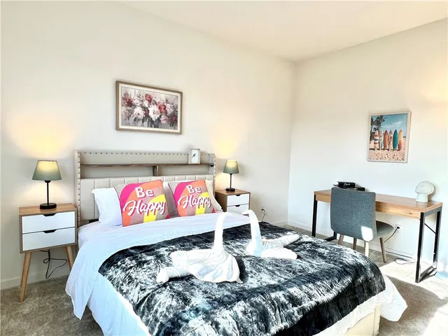 a bedroom with a bed a painting on the wall and a lamp