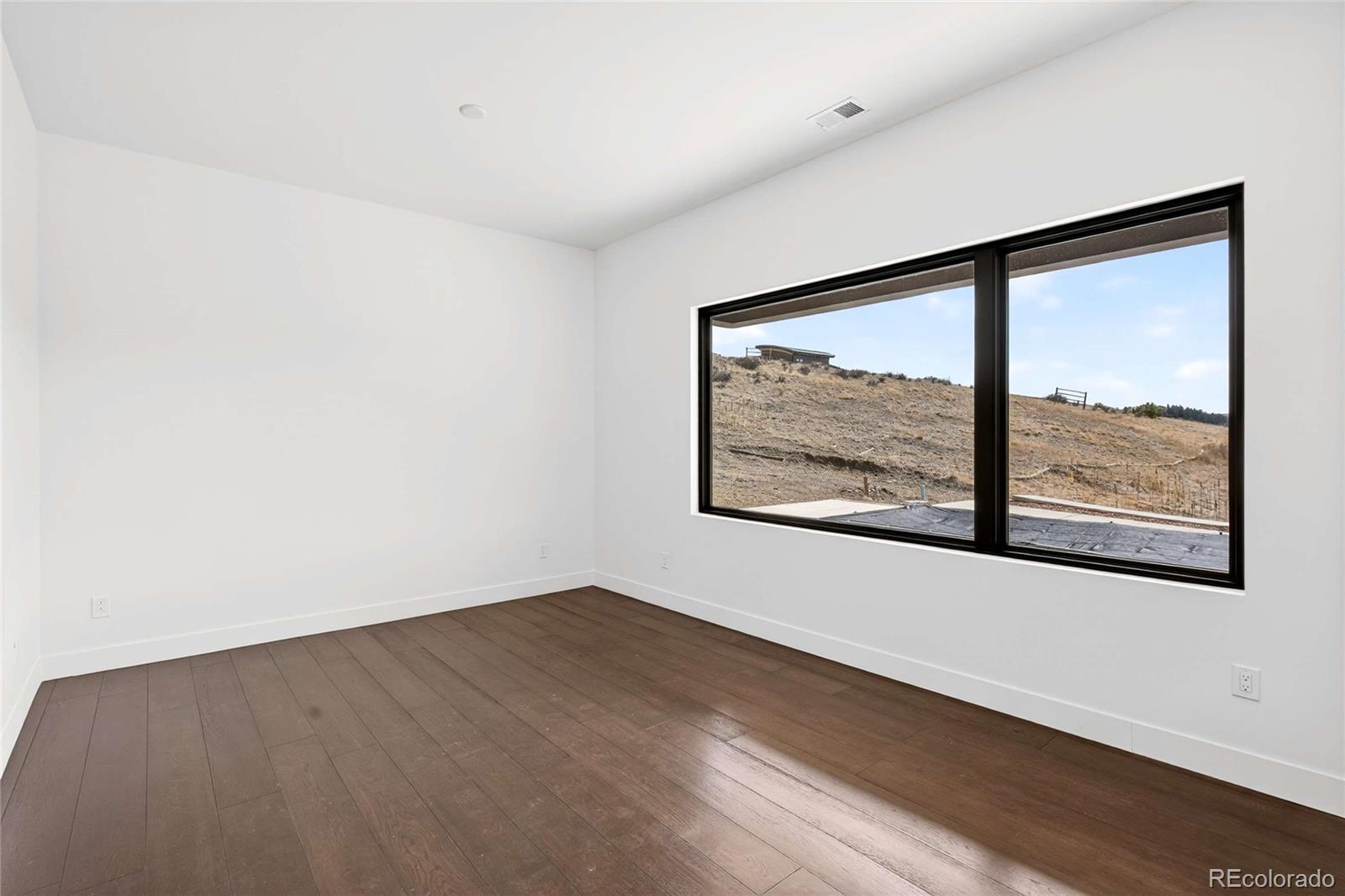 545 Strada Rossa Road Golden, CO 80401 - Photo 19 of 49 an empty room with wooden floor and window