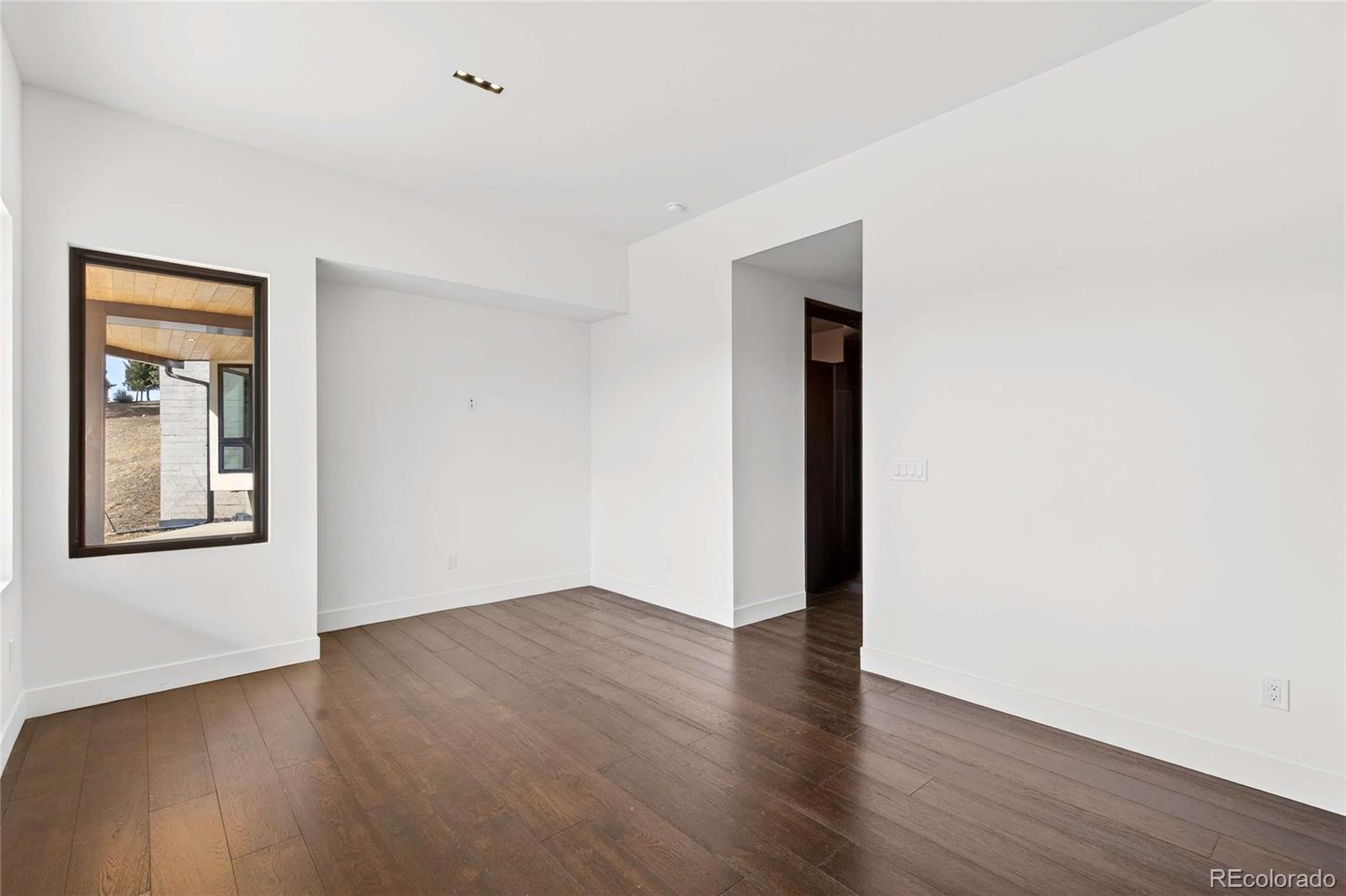 545 Strada Rossa Road Golden, CO 80401 - Photo 20 of 49 an empty room with wooden floor and windows