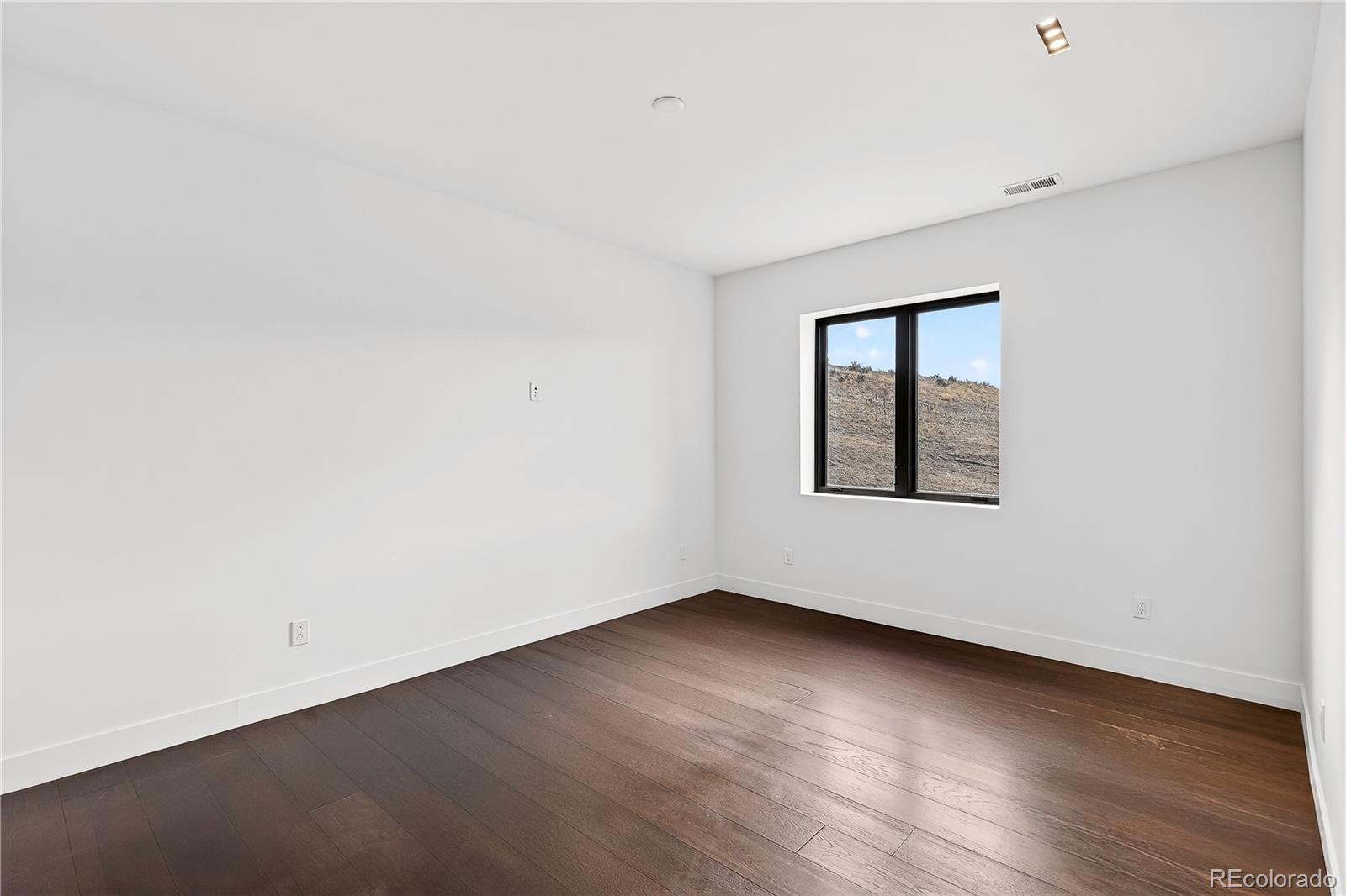 545 Strada Rossa Road Golden, CO 80401 - Photo 47 of 49 an empty room with wooden floor and windows