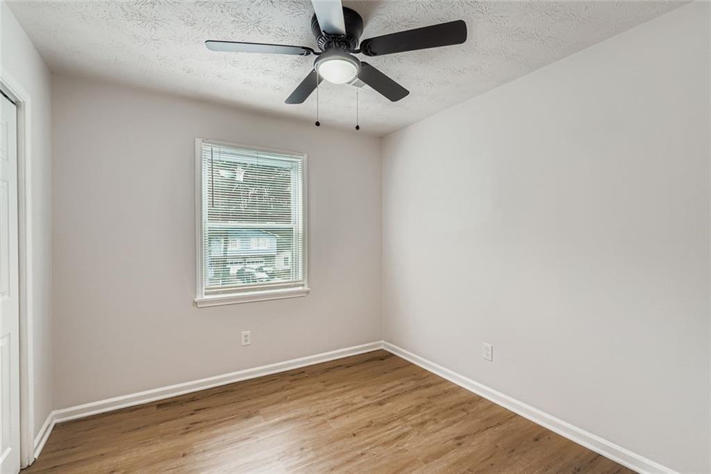 862 Sheppard Way Stone Mountain, GA 30083 - Photo 14 of 22 an empty room with wooden floor ceiling fan and windows
