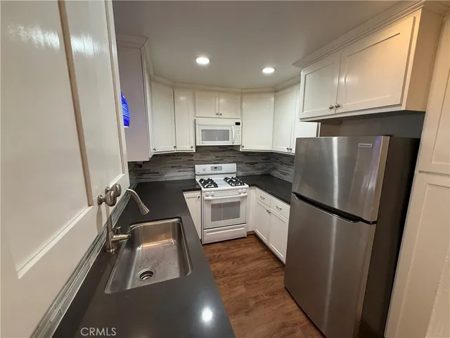 a kitchen with a refrigerator a stove top oven and cabinets