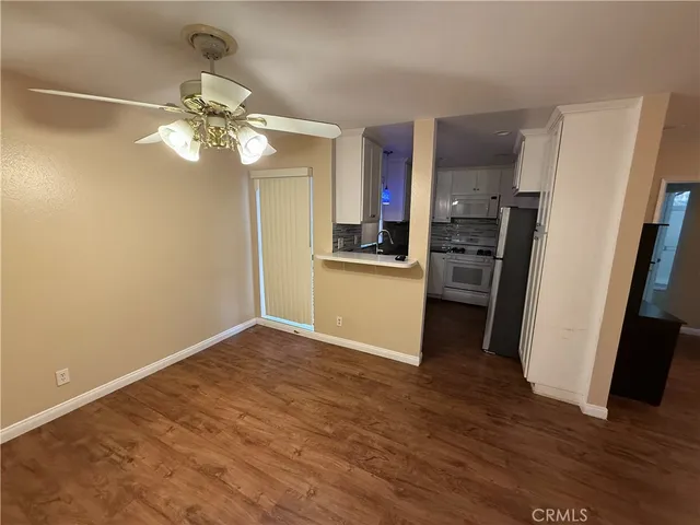 a view of a kitchen with a refrigerator a ceiling fan and wooden floor