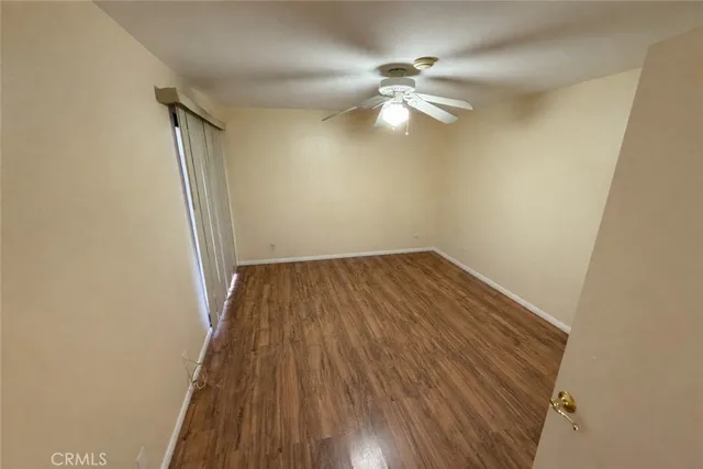 an empty room with wooden floor fan and windows