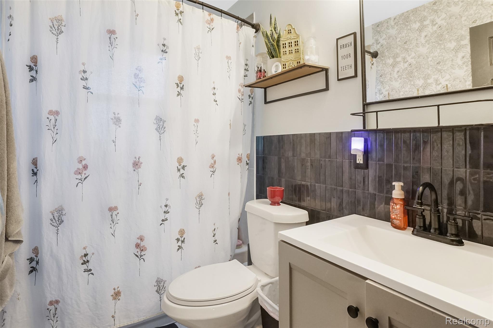 8330 Baldwin Road Gaines, MI 48436 - Photo 14 of 27 White single basin vanity with matte black faucet, dark rectangular wall tiles, and wall-mounted mirror