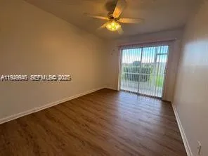 an empty room with wooden floor and fan
