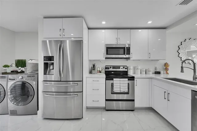 a kitchen with stainless steel appliances granite countertop a refrigerator a stove a sink and a microwave